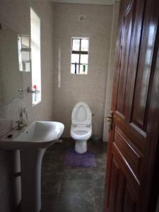 een badkamer met een wit toilet en een wastafel bij Serene Modern 3 bedroom house near Mombasa Road in Emali