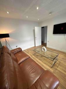 sala de estar con sofá de cuero y TV de pantalla plana en Dallas House - Easy links to LHR and London, en Hayes