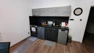 a kitchen with black counters and a clock on the wall at Apartman PAVLOVIC 1 in Dedinje