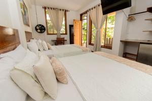 1 dormitorio con 3 camas con almohadas blancas en Villa Lu Amazon Ecolodge, en Tarapoto