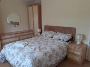 een slaapkamer met een bed, een dressoir en een spiegel bij silver way in Highcliffe