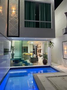 a swimming pool in a house with a living room at Casa Brilho da Lua - 3 Suítes, apenas 300m da Praia in Porto Seguro