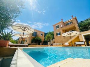 a swimming pool in front of a building with umbrellas at Homer's View in Stavros