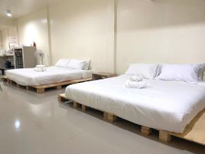 two beds in a room with white sheets and towels at Studio townhouse near Airport and old town Chiang Mai in Chiang Mai