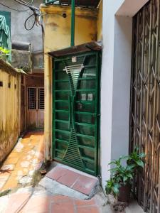 uma porta verde que leva a um edifício com uma escada em H2 homestay phố cổ check in tự động em Hanói
