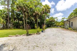 a gravel driveway with palm trees in a yard at Escape to Our Private Guest House in Jupiter Farms in Jupiter