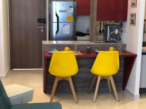a kitchen with two yellow chairs in front of a counter at Flat Versatti - Próximo Real Hospital Port e Pólo Médico Ilha do Leite in Recife