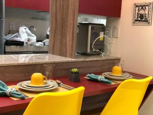 a dining room table with yellow chairs and a kitchen at Flat Versatti - Próximo Real Hospital Port e Pólo Médico Ilha do Leite in Recife