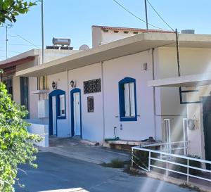 a white building with blue doors on a street at Villa Nelparadi in Plátanos
