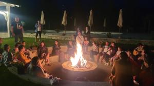 a group of people sitting around a large fire at Natura Family Resort in Avrig