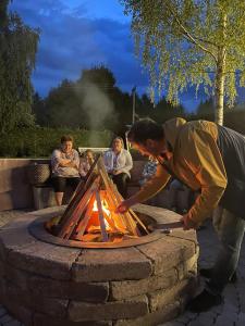 a man bending over a fire in a fire pit at Natura Family Resort in Avrig