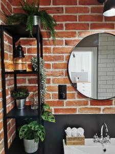 ein Badezimmer mit einem Spiegel an einer Backsteinwand in der Unterkunft APARTAMENT GDAŃSKA FLORA in Danzig