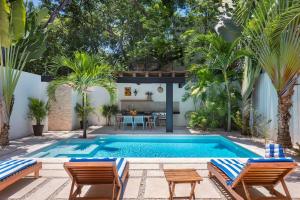 una piscina en un patio trasero con 2 sillas y una mesa en Wonderful Tropical Home 3BR, Garden, Private Pool. en Tulum