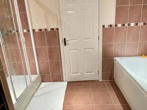 uma casa de banho com um chuveiro, uma banheira e uma porta em Large Executive 4-Bed Detached House in Miskin, Cardiff-sleeps up to 10 em Hensol