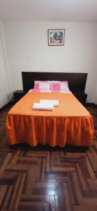 1 dormitorio con 1 cama con sábanas de color naranja y almohadas rosas en HOSPEDAJE CALLAO, en Tacna