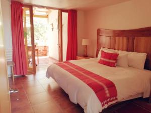 a bedroom with a large bed with a red and white blanket at Casa Tsaya Hotel Boutique in Bernal
