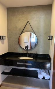 a bathroom with a sink and a mirror at Sonia Flats - Chalé a 500 metros da Praia da Tartaruga in Búzios