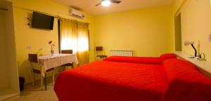 Habitación de hotel con cama roja y mesa en Bari en Mendoza