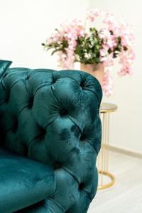 a green couch sitting next to a table with flowers at Legato Apartment in Brčko