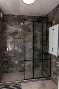 a shower in a room with a stone wall at Legato Apartment in Brčko