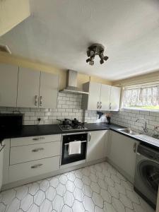 a kitchen with white cabinets and a stove top oven at Charming Four Bedroom Holiday Home in Harlow