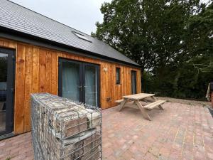 a wooden cabin with a picnic table and a bench at 1 - Fox Burrow, Norfolk Norwich in Sparham