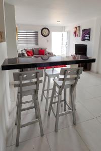 a kitchen with a table and stools with a couch at Apartamentos amoblados Margaritas in Ríohacha