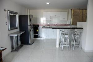 a kitchen with a black refrigerator and bar stools at Apartamentos amoblados Margaritas in Ríohacha