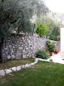 a stone wall next to a yard with trees at La Casa sul Lago Apartments - Lemon Tree Apartment in Limone sul Garda