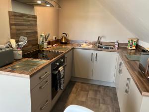 a kitchen with white cabinets and a sink at Vicki's Den in Tain