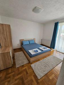 a bedroom with a bed with blue sheets and two rugs at Central apartment in Prilep in Prilep
