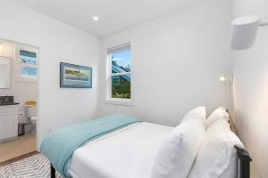 een witte slaapkamer met een bed en een raam bij The Greenwood Gem in Seattle