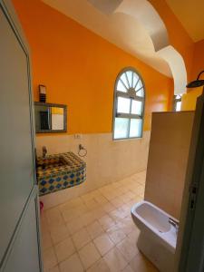 La salle de bains orange est pourvue de toilettes et d'un lavabo. dans l'établissement Dar Ez-zine, à Ounara