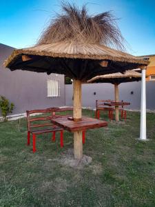 a picnic table with a straw umbrella and two benches at Complejo EQUE PORA in Federación