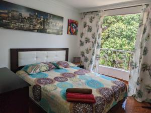 a bedroom with a bed and a large window at Hospedaje Casa Aurora in Cali