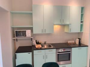 a kitchen with white cabinets and a sink and a microwave at Royal South - Apartment Antwerp with Parkview in Antwerp +26 photos