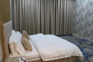 a bed with white sheets and pillows in a bedroom at شقق بيت المدينة للشقق المخدومة in Qabāʼ