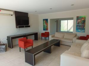 LS Hotel في سالتا: غرفة معيشة مع أريكة وكراسي حمراء
