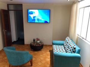 a living room with two chairs and a tv on the wall at Hermoso departamento en lugar centrico in Trujillo