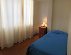 a bedroom with a bed and a lamp on a dresser at Hermoso departamento en lugar centrico in Trujillo