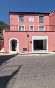 un edificio rosa con dos plazas de aparcamiento enfrente en Residence Mirella, en Acquafredda