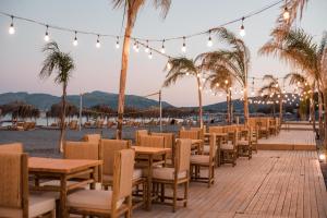 una fila di tavoli e sedie su una spiaggia con palme di Alia Luxury Suites and Spa a Haraki
