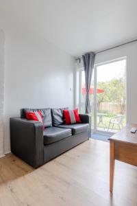 a black couch in a living room with a window at Cosy 2 bedroom apartment near WEMBLEY, garden, late check in in London