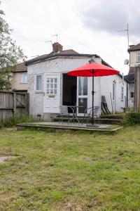 a red umbrella in a yard with a house at Cosy 2 bedroom apartment near WEMBLEY, garden, late check in in London