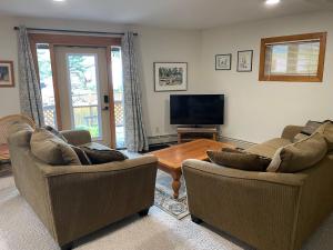 ein Wohnzimmer mit 2 Sofas, einem Tisch und einem TV in der Unterkunft Cedar House in Jasper