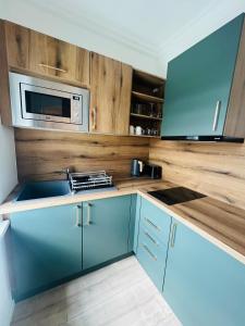 uma cozinha com armários azuis e um micro-ondas em Sofia Apartment & Zimmer Knittelfeld em Knittelfeld
