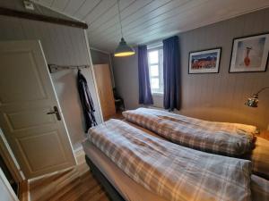 two beds in a room with a window at Autentisk rorbu in Moskenes