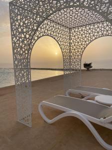 a white bed on the beach with the sunset at Villa La Falaise in Oualidia