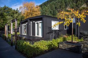 a black tiny house in a garden at Pinewood Lodge and Apartments in Queenstown