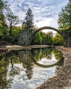an old stone bridge over a pond in a park at Bauwagen Gnubbel am Jahnteich in Weißwasser